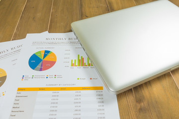 silver laptop and chart document on wooden backbround