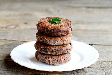 Delicious bean burgers on a plate isolated on old wooden background.  Vegetarian burgers cooked of  boiled red beans chopped with a blender, garlic, eggs, flour and spices. Closeup
