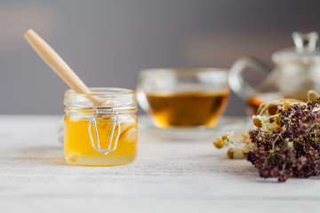 Honey in a glass jar and herbal tea. Honey and tea. Soft focus