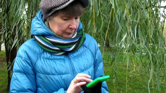 Женшина разговаривает по телефону на фоне ивы осенним вечером/ Телефонный разговор