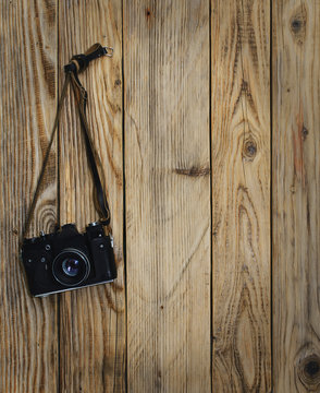 Old black camera hanging on the wood wall.