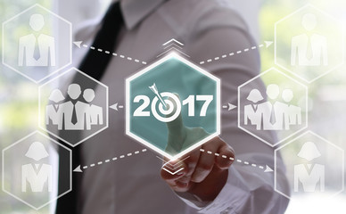 Business, technology and internet concept - businessman presses button 2017 with a target on virtual screens. Icon 2017 instead of zero target. Business concept, webinar screen. Business in 2017.