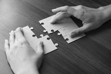 Close-up Of Businessman Hands Completing Jigsaw Puzzle