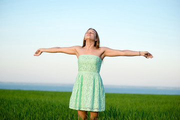 Happiness woman stay outdoor under sunlight of sunset. With raised hands at the sunrise time.