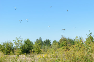 Paratroopers descend to earth on the blue clear sky background