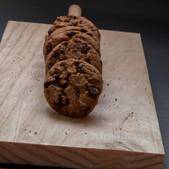 Chocolate cookies on a wooden cutting board. Black background.