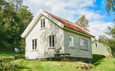 Old white traditional Norwegian house, around the birch forest