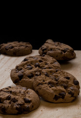 Chocolate cookies on a wooden cutting board. Black background.