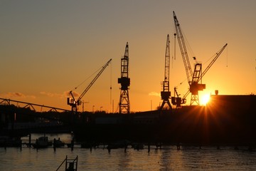 Schiffswerft mit Kränen und untergehender Sonne in Kiel 