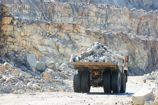 Huge dump truck transporting granite rock or iron ore