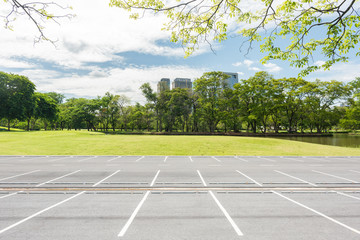 Empty parking lot against green lawn in city park