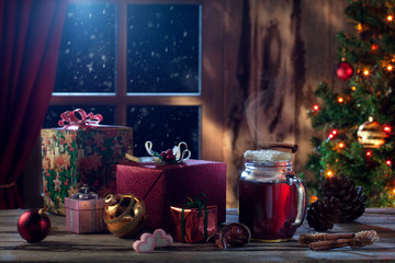 close up view  of glass with mulled wine with gift boxes on color back