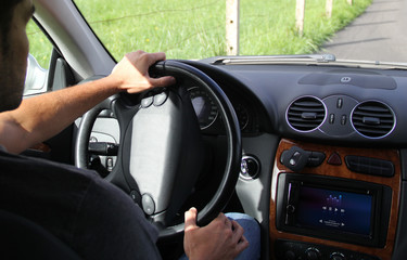young man driving a  car with music on on-board computer