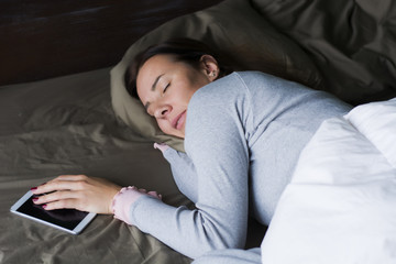 Sleeping young woman holding a smart phone
