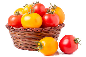 red and yellow tomatoes in a wicker basket isolated on white background