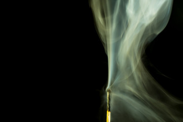 A half burned matchstick smoking in the darkness