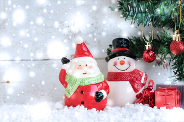 Santa Claus with snowman and snowfall over fir tree