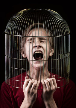 Teenager with the head inside a birdcage, concept