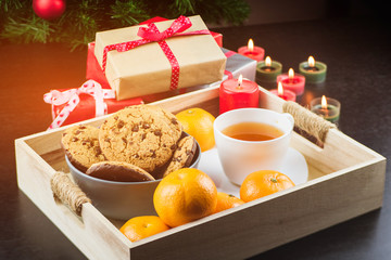 Close-up of mandarins, candles, chocolate cookies, tea and gifts