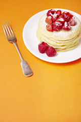 A stack of berry covered pancakes on a bright orange background forming a page header