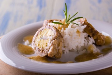 Portion of meat roll filled by eggs and rice on white plate