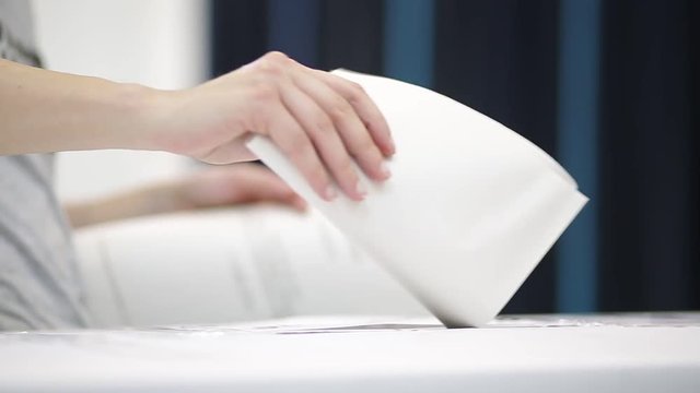 Unrecognizable people cast their vote during elections in a voting station