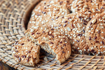 homemade oatmeal cookies with seeds of cereals in wicker plate for a healthy breakfast, close-up, horizontal