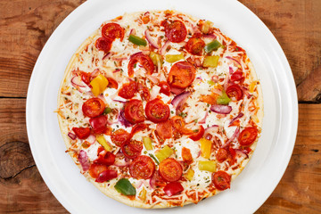 Pizza con tomate y mozzarella sobre una tabla de madera rústica. Vista superior