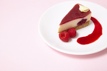 A slice of raspberry cheesecake pudding on a pastel pink background forming a page border