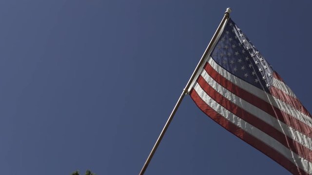 Rustic looking American flag waving on fence post outside of country home.
