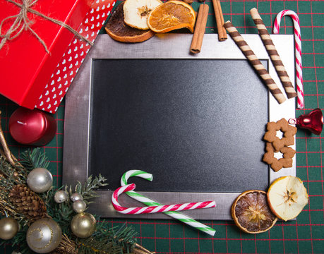Chalkboard decorated with Christmas decorations like gingerbread cookies, candies and baubles. 