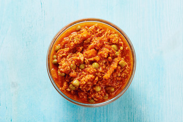 Bolognese sauce in glass bowl on blue table