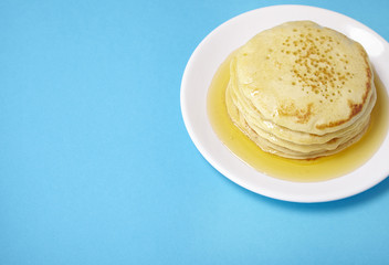 A stack of pancakes with golden syrup on a bright blue background forming a page border