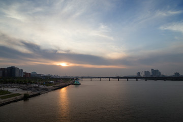 Fototapeta na wymiar View of a park in the river shore and bridge at the Han River in Seoul, South Korea, at sunset. Copy space.