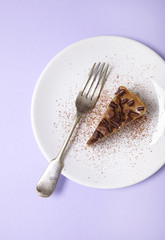 A slice of toffee cheesecake dessert on a pastel purple background