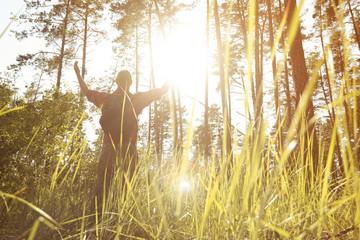 Man raised his hands to the sun in the middle of the forest