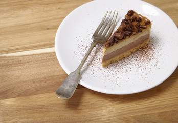 A slice of toffee and chocolate cheesecake dessert on a wooden background