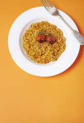 A dinner dish of tomato risotto on a bright orange background forming a page header