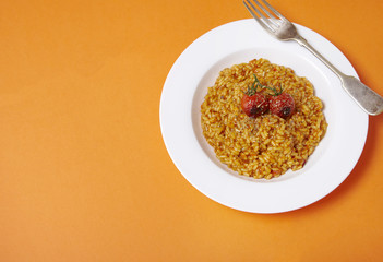 A dinner dish of tomato risotto on a bright orange background forming a page border