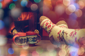 Feet in woollen socks by the Christmas fireplace. Woman relaxes