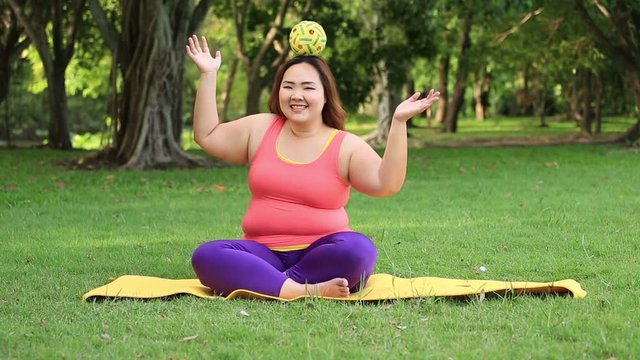 Beautiful fat woman playing with rattan ball on the mat.