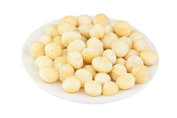 delicious macadamia nuts on  plate on  wooden background
