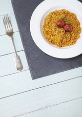 A dinner dish of tomato risotto on a blue wooden table background forming a page header