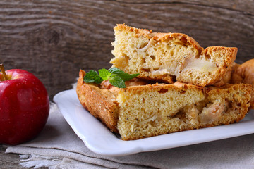 Charlotte with apples in the white plate on a wooden background
