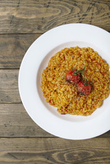 A bowl of tomato risotto on a rustic wooden dinner table background