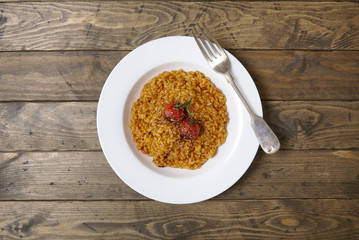 A dish of tomato risotto on a rustic wooden dinner table background