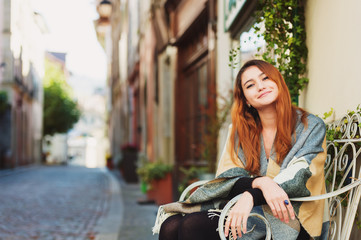 Fototapeta na wymiar Young fashion 20 year old girl sitting on the bench, wearing warm plaid jacket