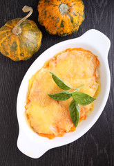 gratin potatoes and pumpkin with milk in a black background