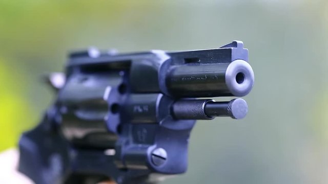 Shots from a revolver. Man shoots a revolver. Shots from a black pistol. Man with black gun, close up
