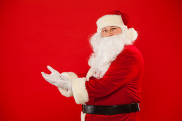 Santa Claus pointing in blank a place, red background